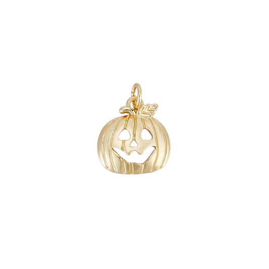 Gold pumpkin charm with a face on a white background