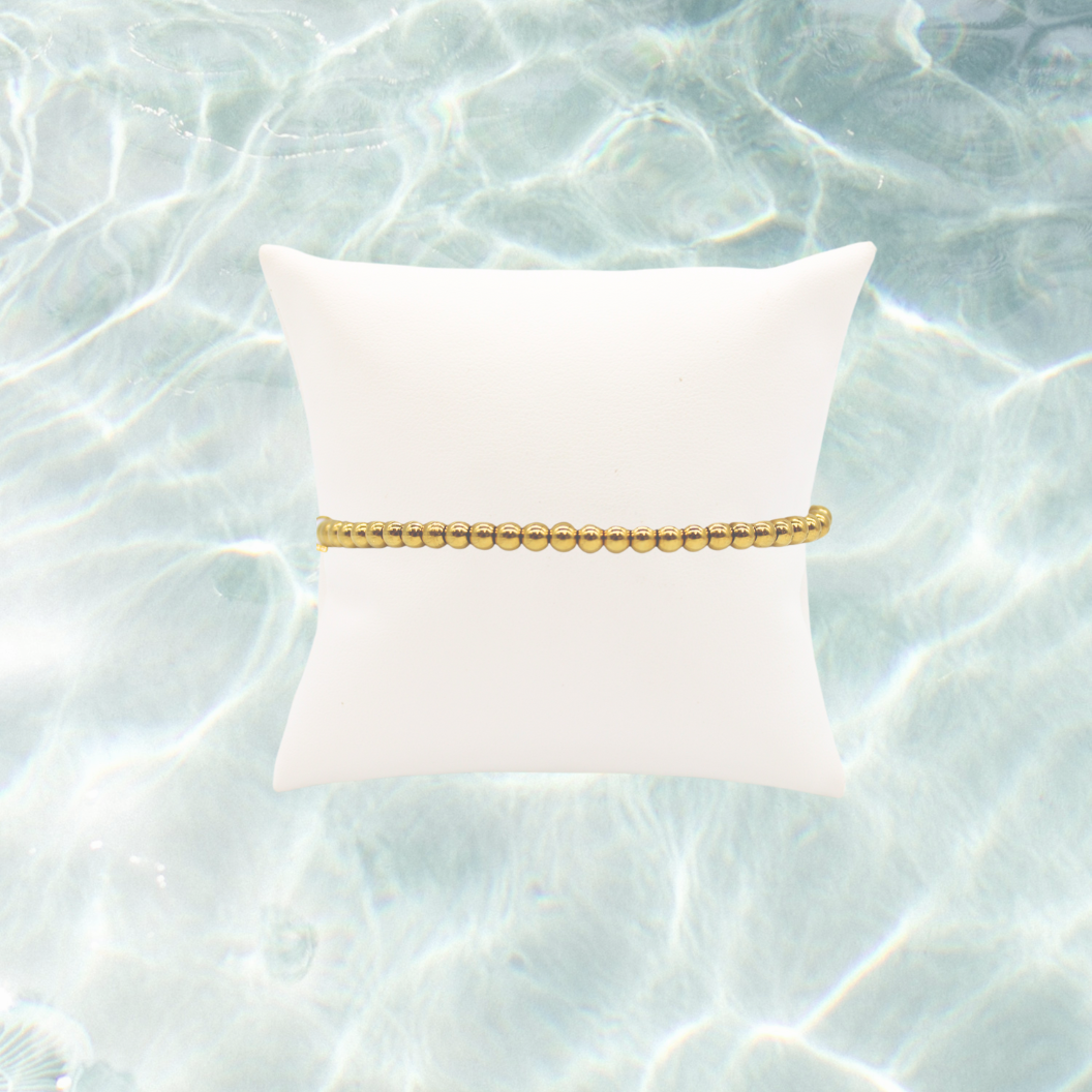 Gold Classic Beaded Bracelet on water background 