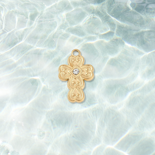 Gold Scrollwork Cross with Rhinestone Center Charm on water background