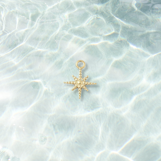 Gold Dewdrop Beaded Star Charm on water background 