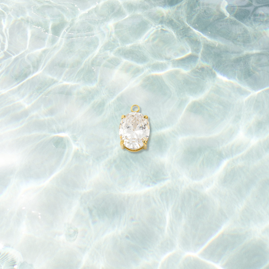 Gold Pure Brilliance Oval Cubic Zirconia Charm  on water background