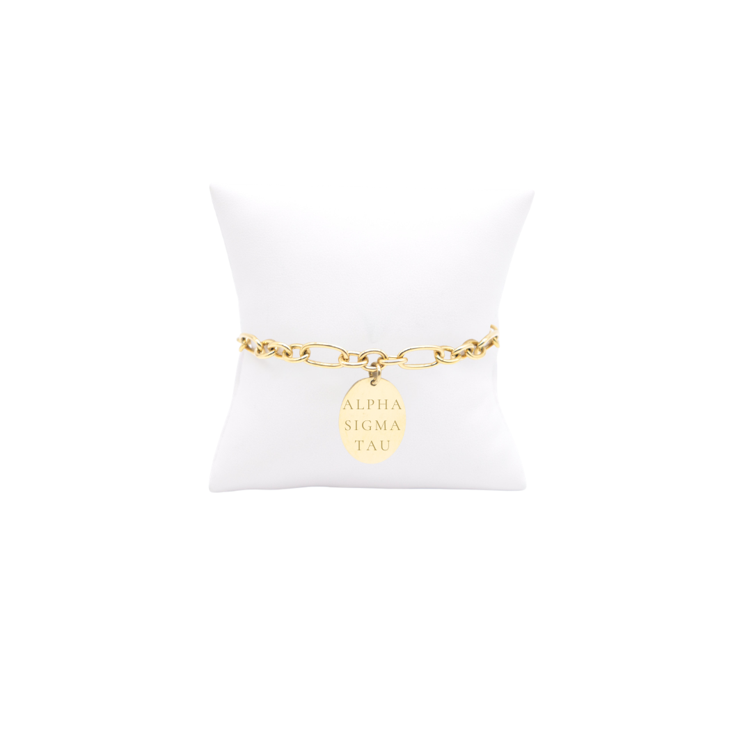 Alpha Sigma Tau gold large link keepsake bracelet with large oval charm displayed on white pillow front view with full sorority name