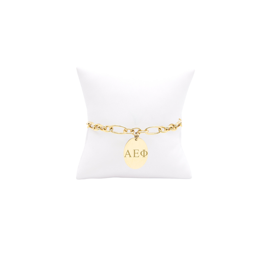 Alpha Epsilon Phi gold large link keepsake bracelet with large oval charm with vertical/stacked greek letters on white pillow front view