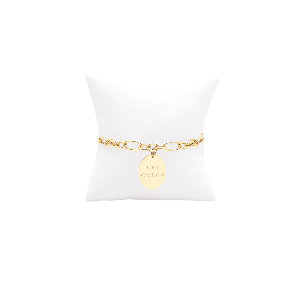Chi Omega gold large link Keepsake bracelet with large oval charm with full sorority name on white pillow front view
