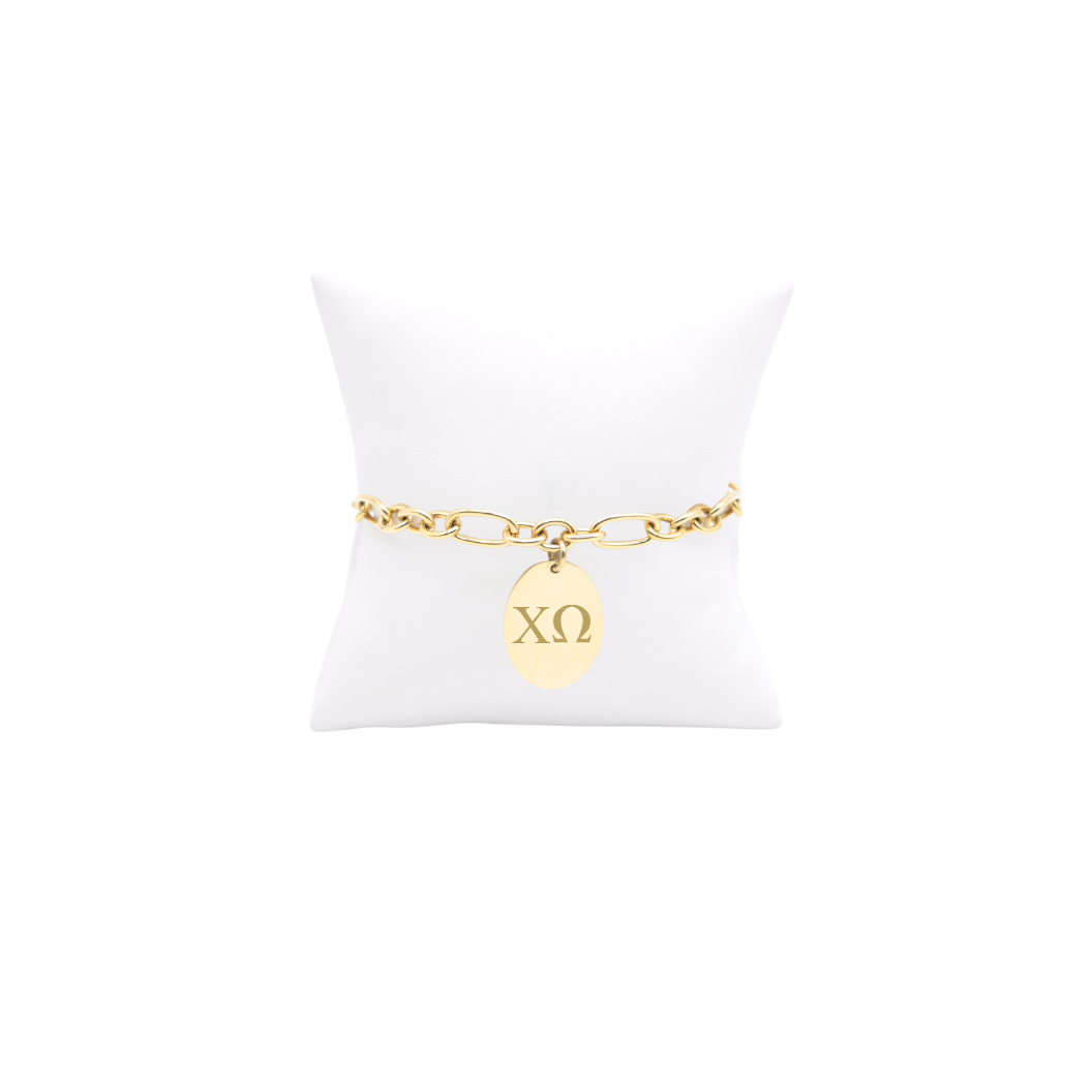 Chi Omega gold large link Keepsake bracelet with large oval charm with horizontal greek letters on white pillow front view