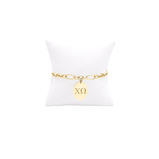 Chi Omega gold large link Keepsake bracelet with large oval charm with horizontal greek letters on white pillow front view