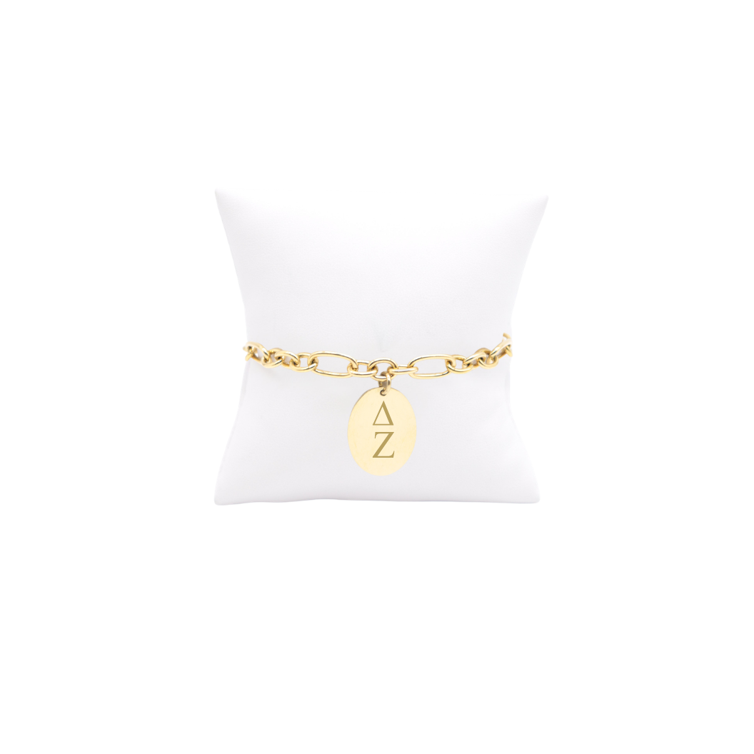Delta Zeta gold large link Keepsake bracelet with large oval charm with vertical greek letters on white pillow front view