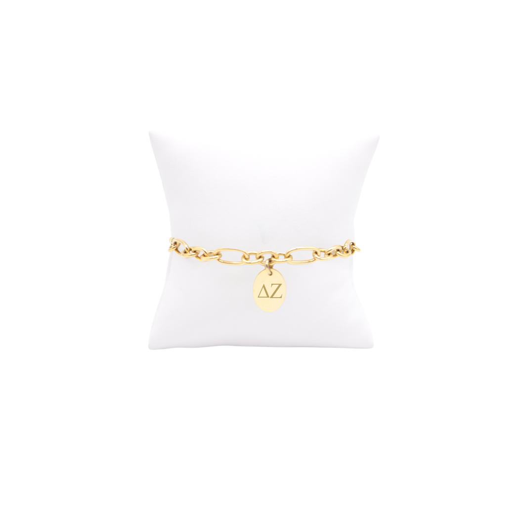 Delta Zeta gold link Keepsake bracelet with small oval charm with horizontal greek letters on white pillow front view