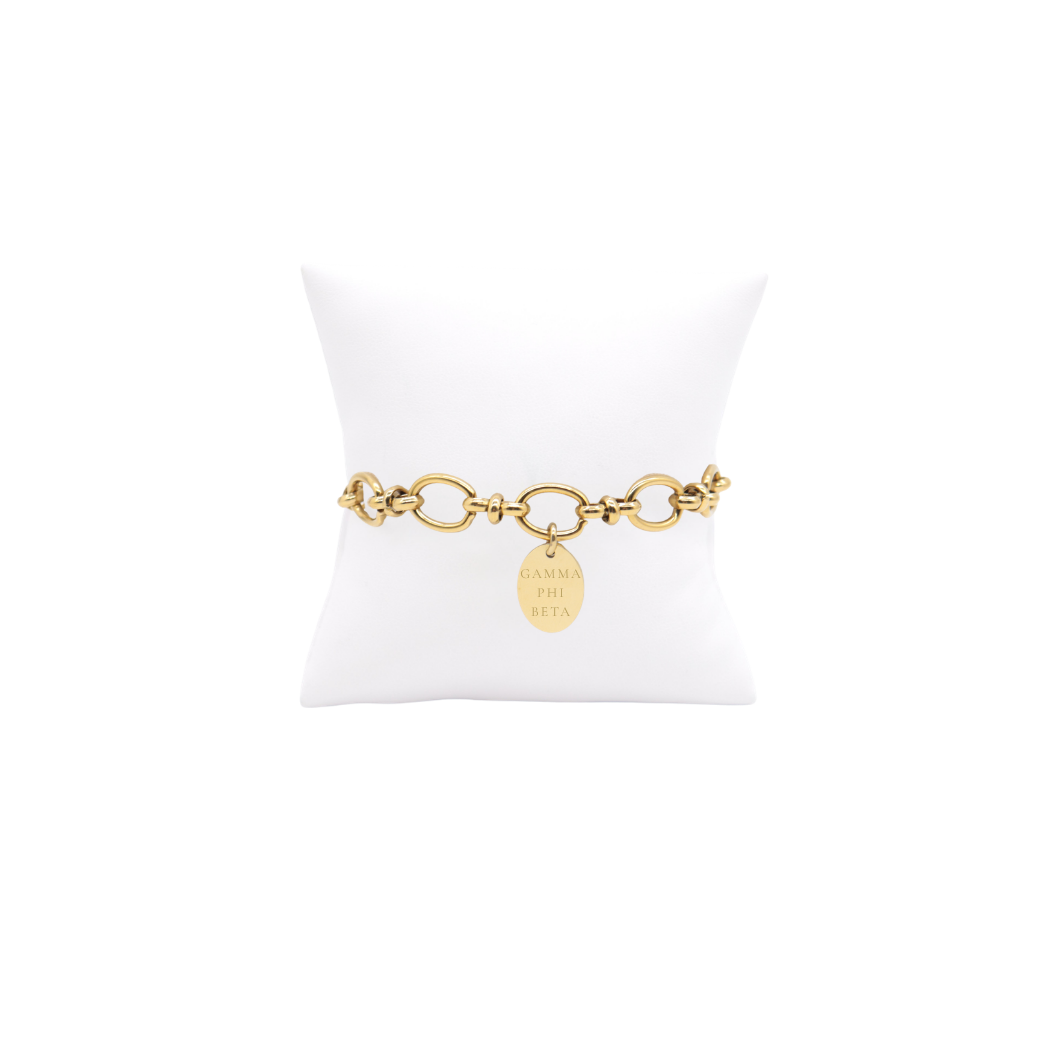 Gamma Phi Beta gold large link evermore bracelet with small oval charm displayed on white pillow front view with full sorority name