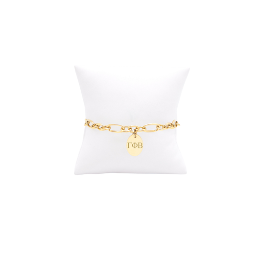 Gamma Phi Beta gold large link keepsake bracelet with small oval charm displayed on white pillow front view with horizontal greek letters