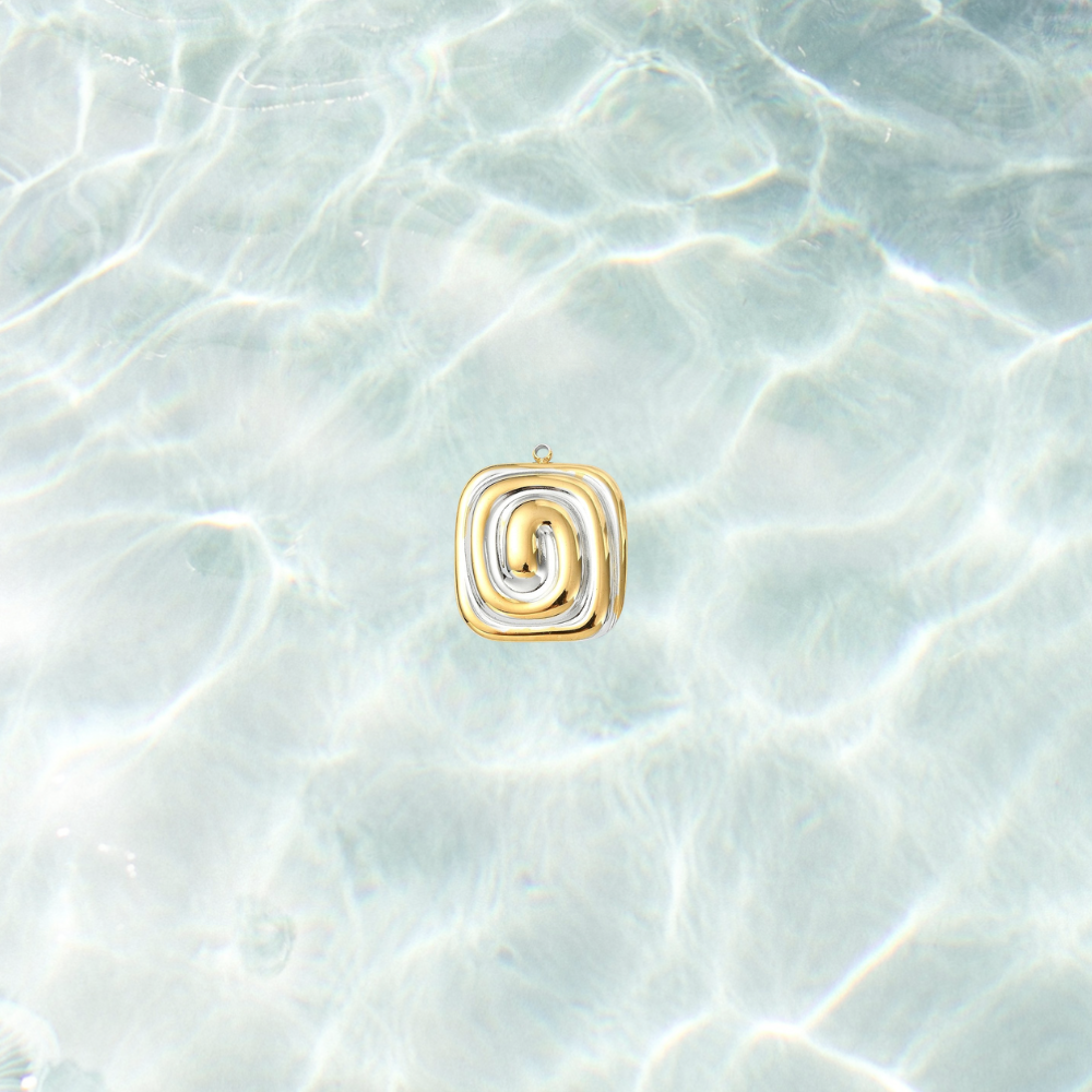 Gold and silver spiral charm with a modern mixed metal swirl design on a shimmering water background.