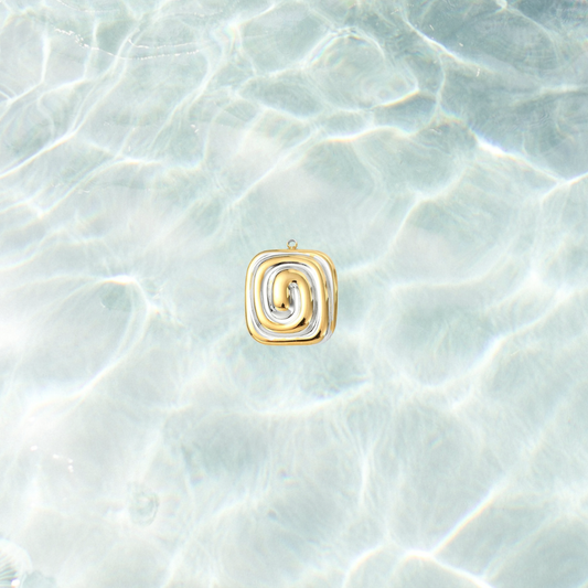 Gold and silver spiral charm with a modern mixed metal swirl design on a shimmering water background.
