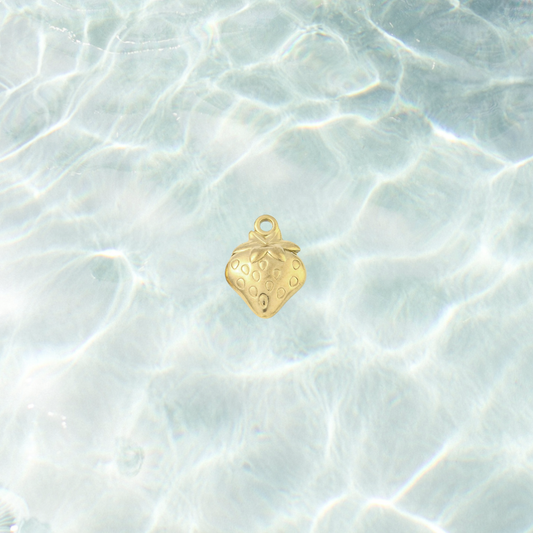Gold fresh picked strawberry charm with a polished finish, embossed seed details and leafy top design on a waterproof background
