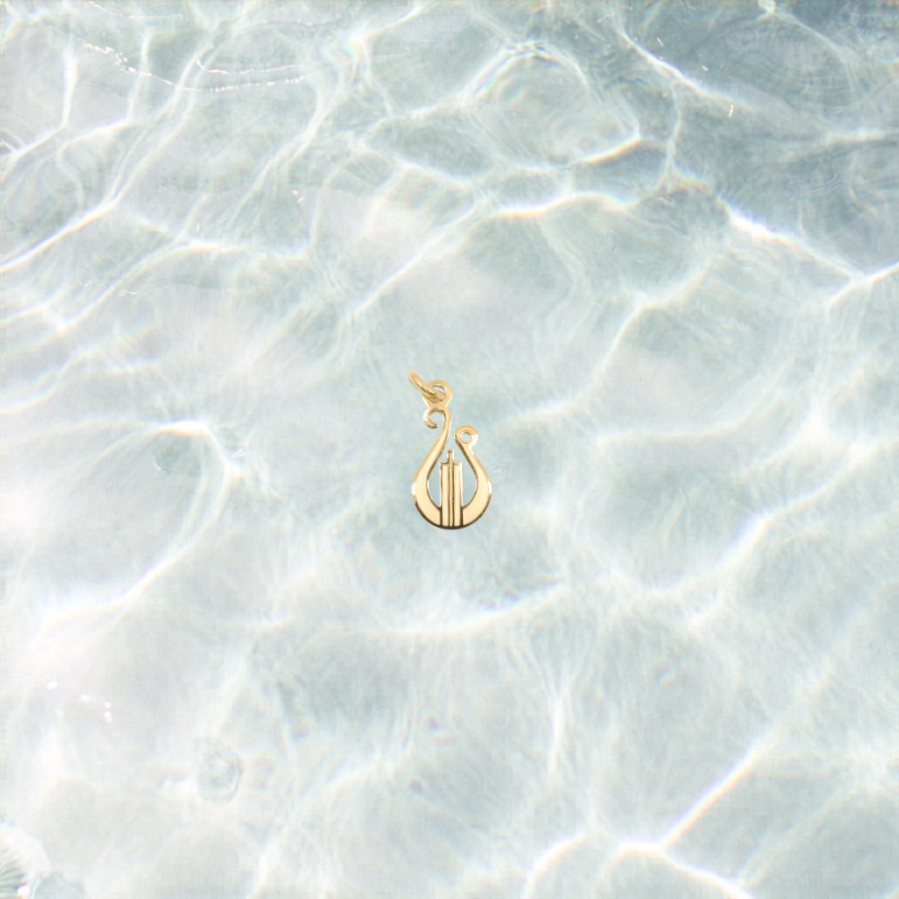 Gold lyre charm on a shimmering water background