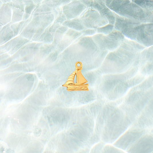 Gold nautical sailboat charm on waterproof background