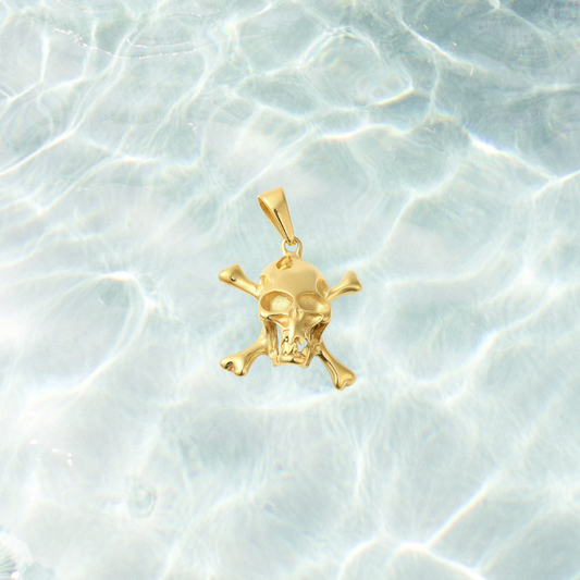 Gold Pirate Skull Charm featuring a detailed skull and crossbones design with a polished gold finish, displayed on a light blue water-inspired background. Perfect for charm necklaces, bracelets, and pirate-inspired jewelry.