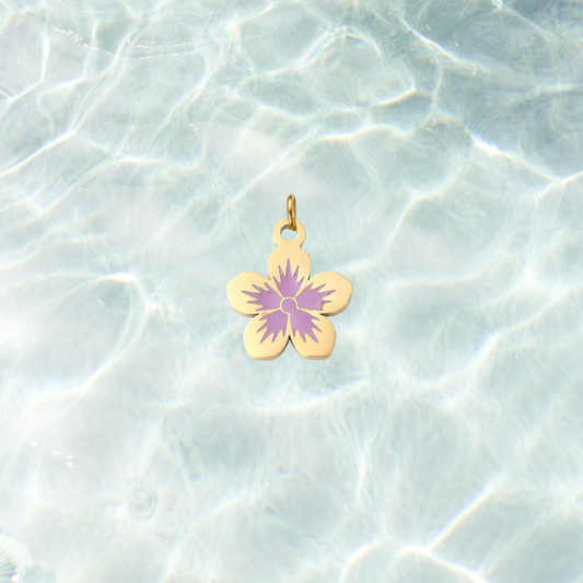 Gold flower charm featuring a five-petal flower design with a lavender purple center on a shimmering water background.
