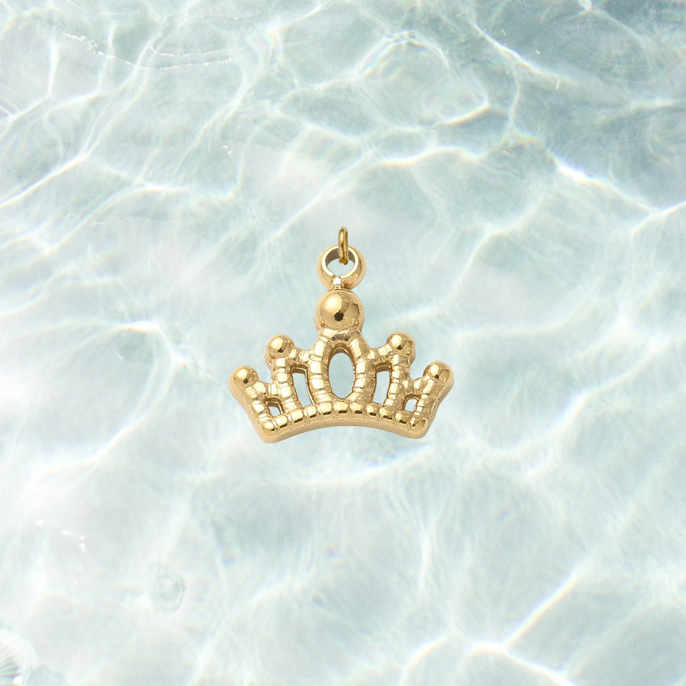 Gold tiara crown charm with an elegant openwork design on a shimmering water background.