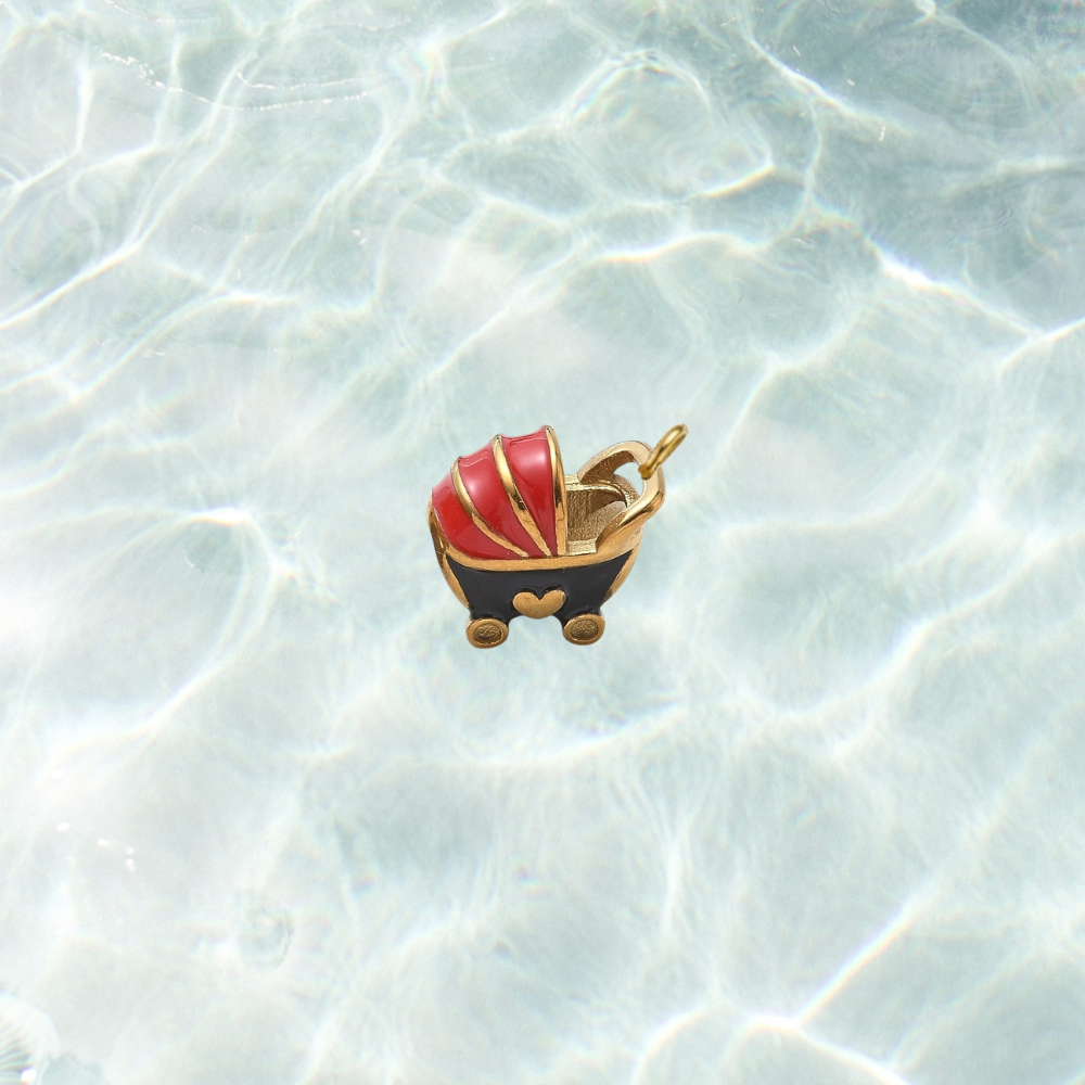 Gold vintage baby carriage charm featuring a red and black enamel baby stroller with gold accents on a shimmering water background.