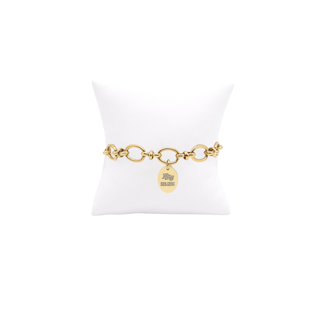 High Point University gold large link Evermore bracelet with small oval charm with high point university text and hpu logo on white pillow front view

