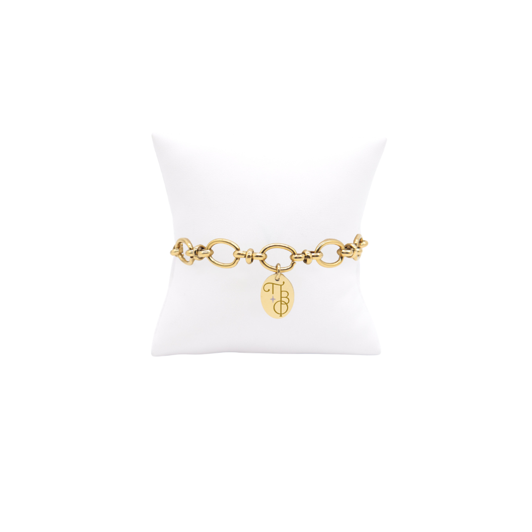 Pi Beta Phi gold large link Evermore bracelet with small oval charm displayed on white pillow front view with new vertical/stacked greek letters