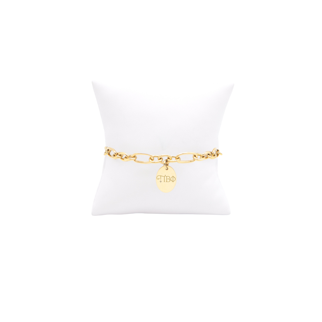 Pi Beta Phi gold large link keepsake bracelet with small oval charm displayed on white pillow front view with new horizontal greek letters