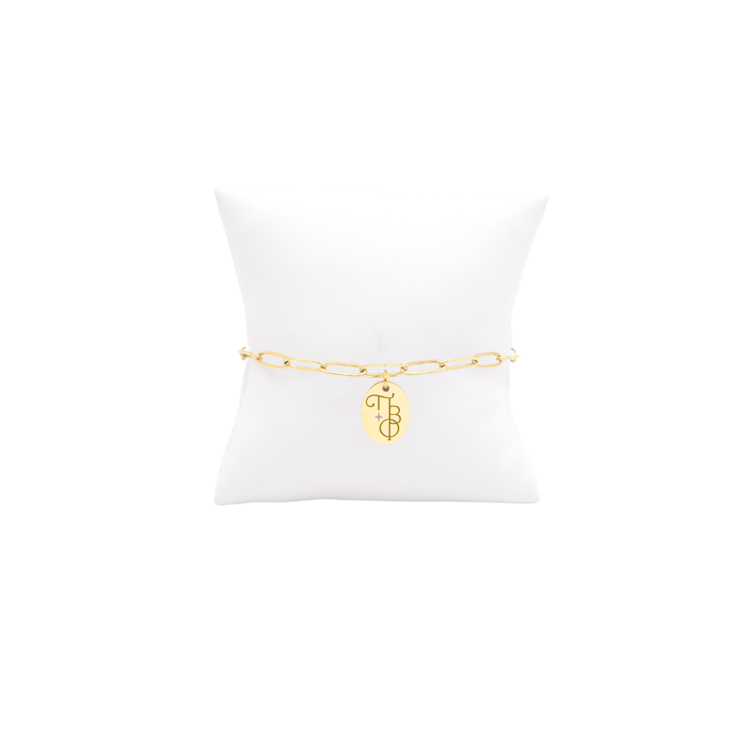 Pi Beta Phi gold link storyline bracelet with small oval charm displayed on white pillow front view with new vertical/stacked greek letters