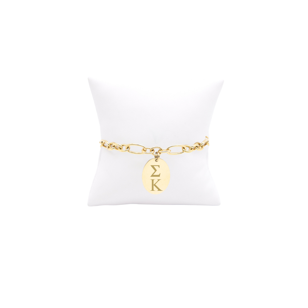 Sigma Kappa gold large link Keepsake bracelet with large oval charm with vertical greek letters on white pillow front view